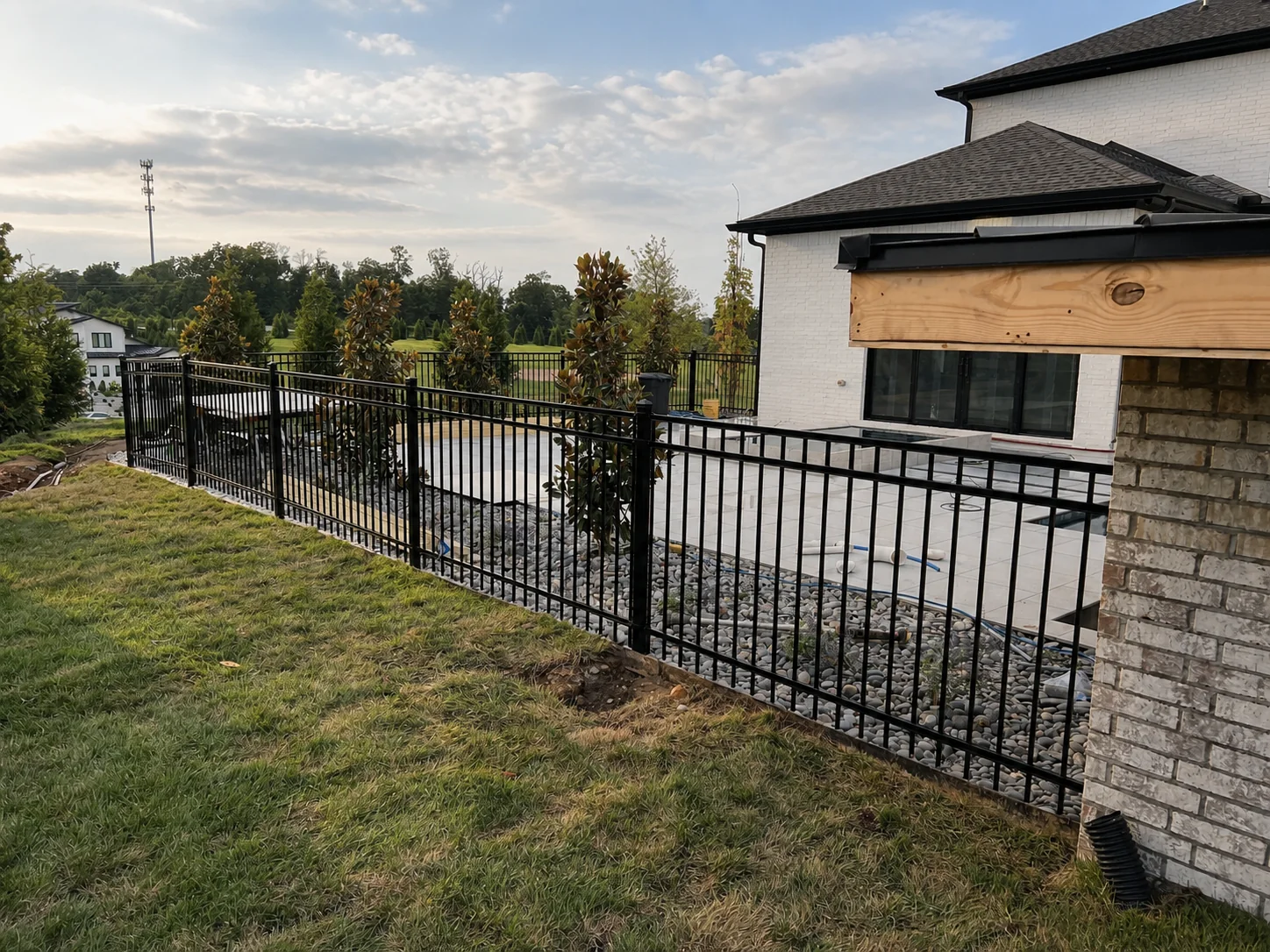 Black ornamental fence along residential landscaping